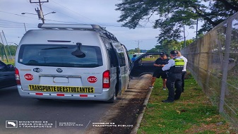 Microbús de transporte especial de estudiantes siendo inspeccionado por oficial de tránsito y person