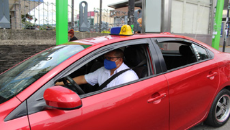 Imagen de taxi rojo y el conductor porta mascarilla
